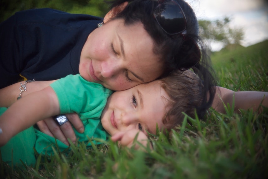 Mother and son laying on green grass.
