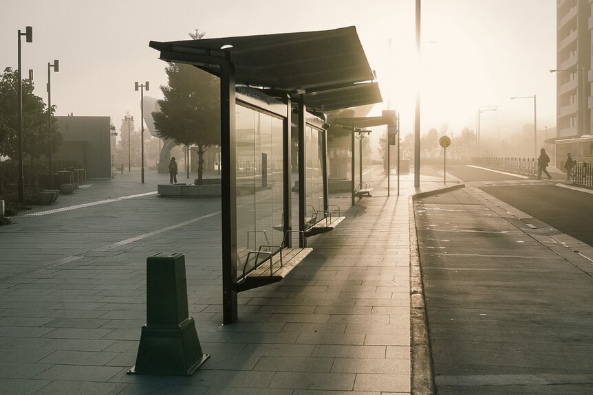 The sun rising over an empty dark bus stop 