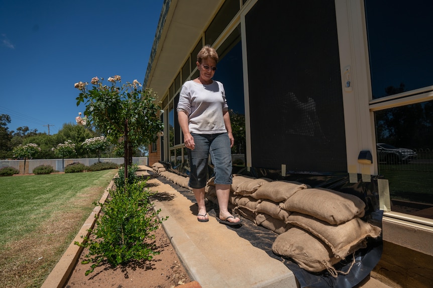 A woman walking beside sandbags stacked outside her house