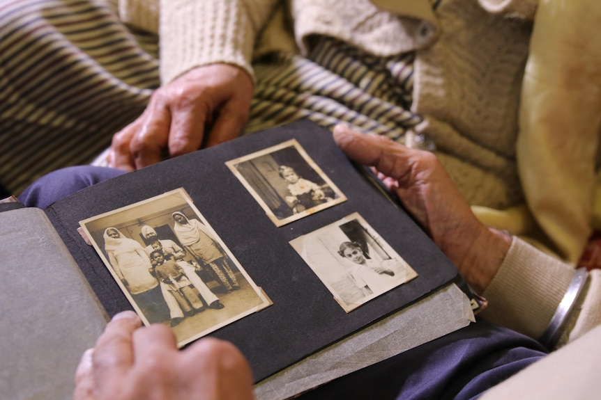 A photo album featuring three black and white photos, one of a family, the other two of children