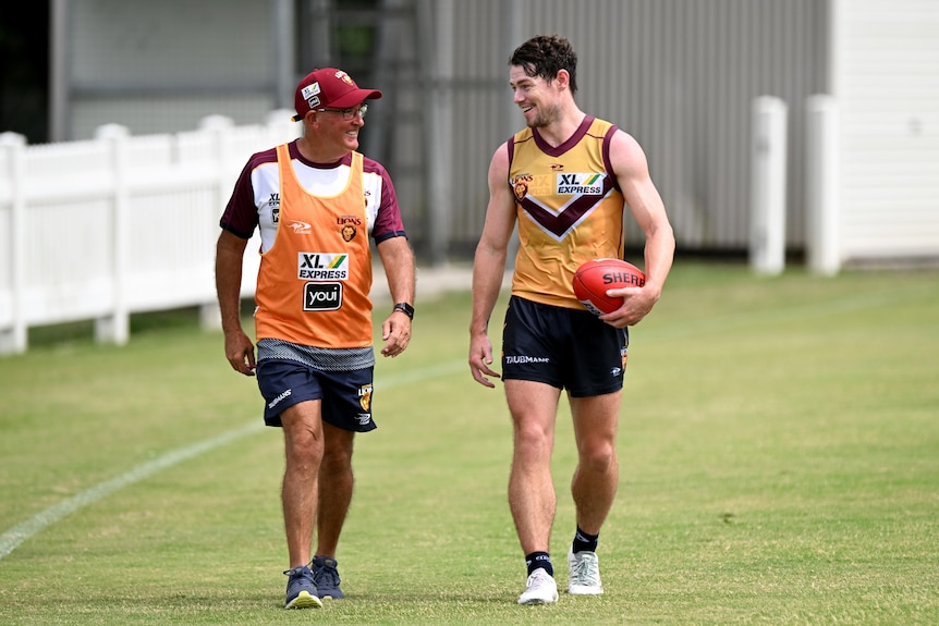 Chris Fagan and Lachie Neale both smile as they walk together along the boundary line