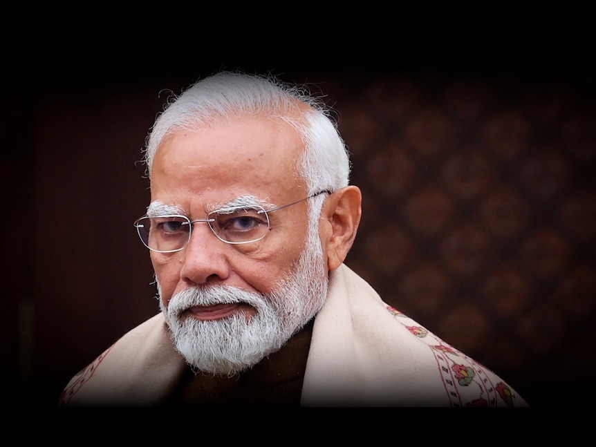 Narendra Modi looks directly into camera while wearing rimless glasses and a beige stole