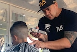 A man cuts the hair of a child in a mobile barber shop.