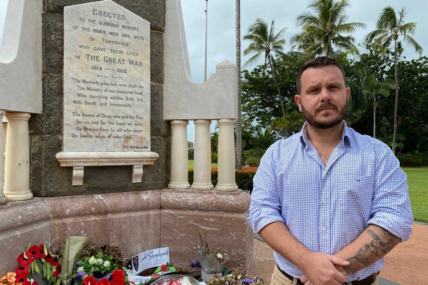 Phillip Thompson stands next to a war memorial