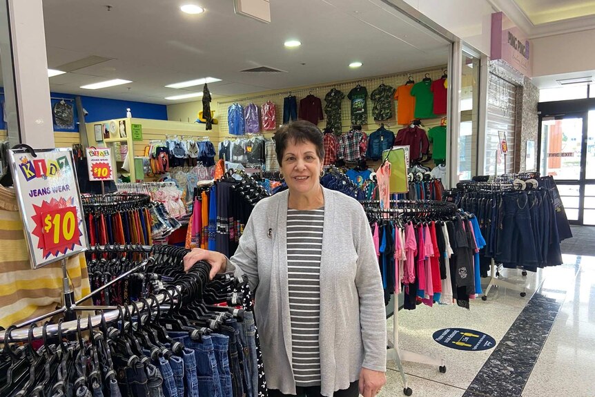Liz Bryson stands next to a rack of jeans in her kids clothing store.