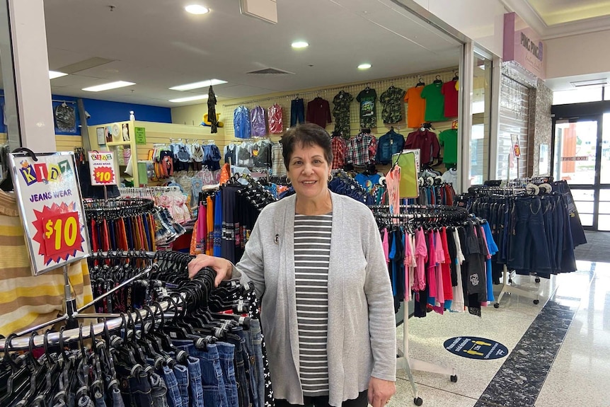 Liz Bryson stands next to a rack of jeans in her kids clothing store.