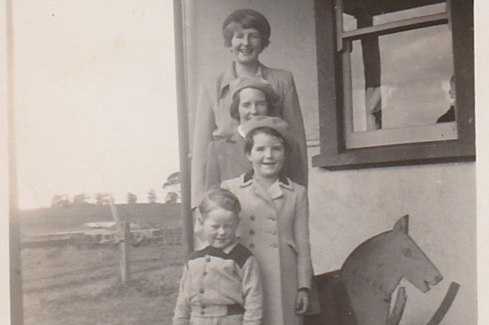 a young boy stands in front of three girls