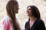 Two women laugh and smile as they talk.
