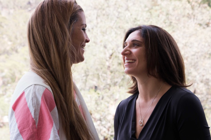 Two women laugh and smile as they talk.