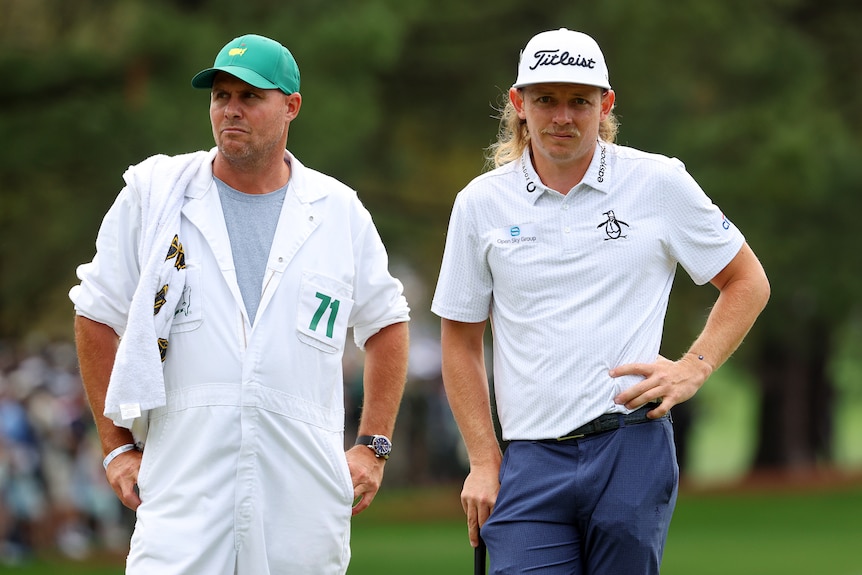A golfer stands with his caddy during a round