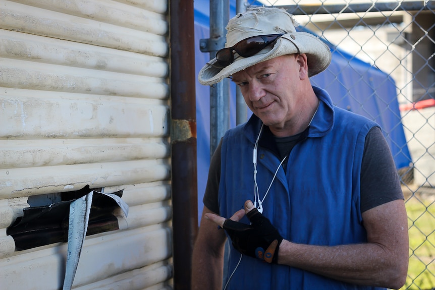 Removalist Roden Woodhams points to a hole in the wall inside of which he can see asbestos.