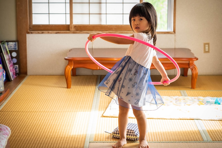 A young girl with a hula hoop.