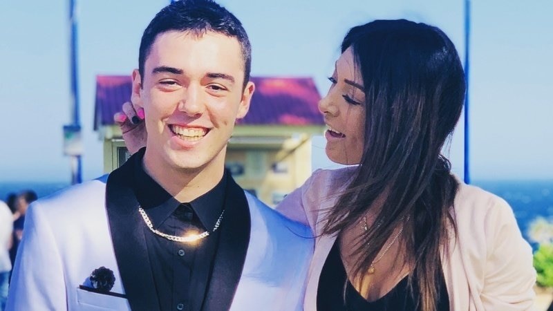 A young man in formal wear poses with his mother.