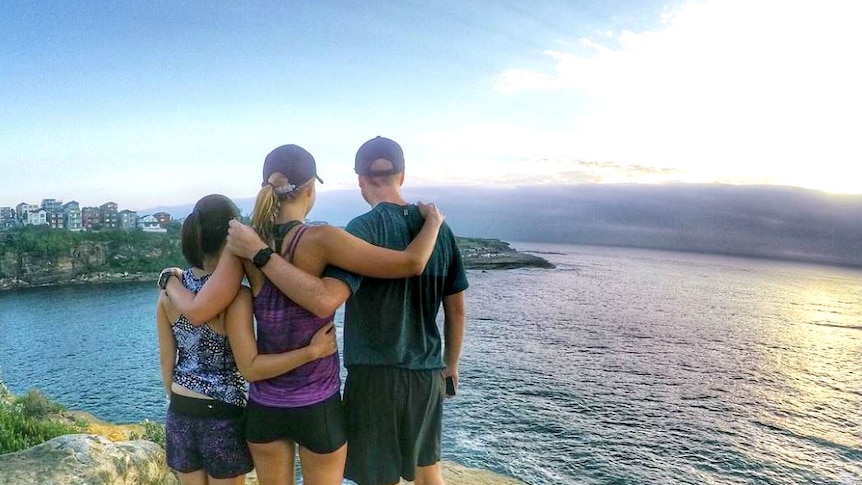 Three runners overlooking looking out over the ocean