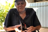 An elderly Indigenous man holding a medal