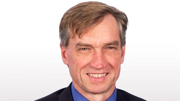 A smiling man in a suit with light brown hair