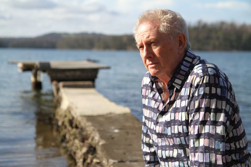 A man near a lake looking pensive out into the distance