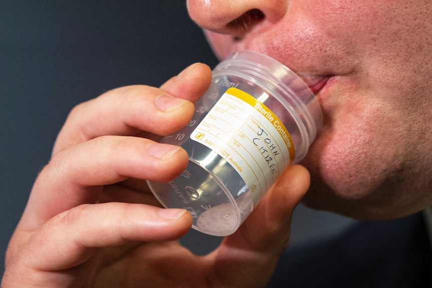 A man spits into a specimen jar