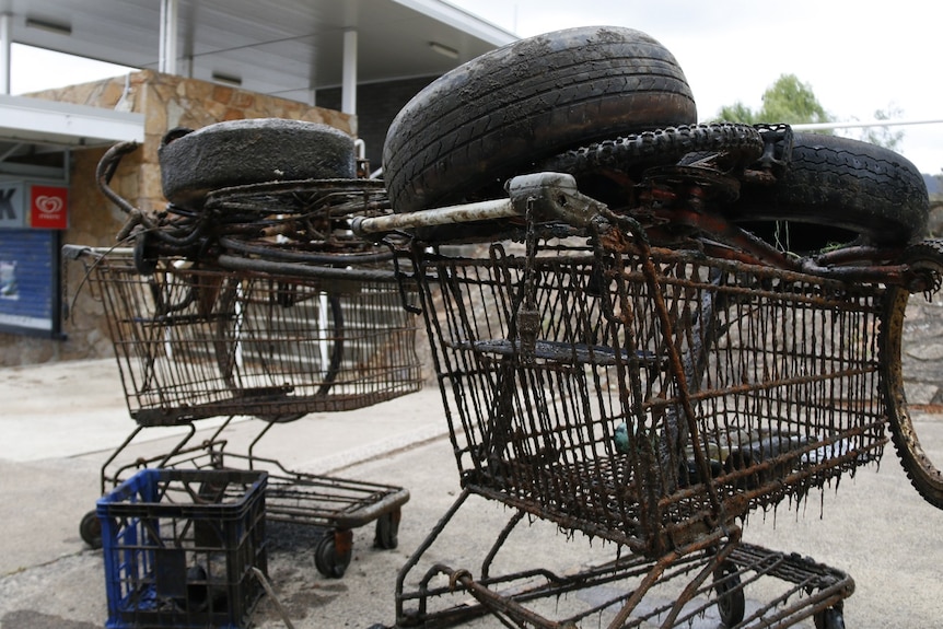 Rusted shopping trolleys stacked with tires and old bikes.