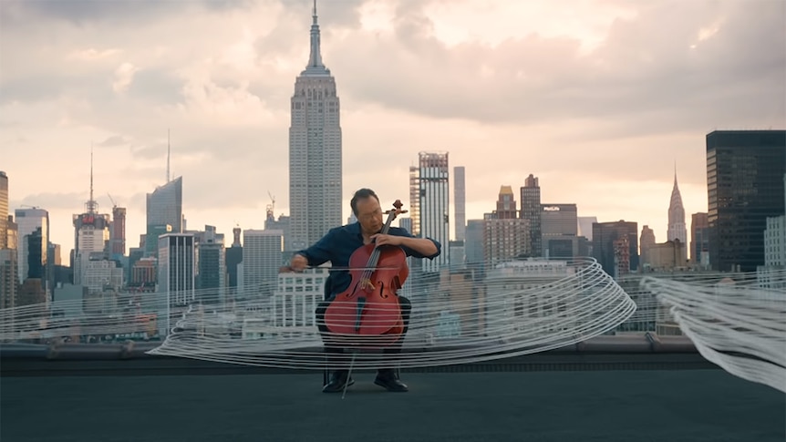 Yo-Yo Ma plays cello on a rooftop in New York City. The Empire State Building is in the background.