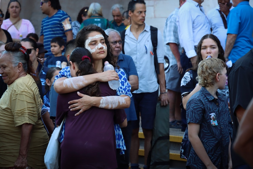 Two women hugging outside of a church after a funeral service.