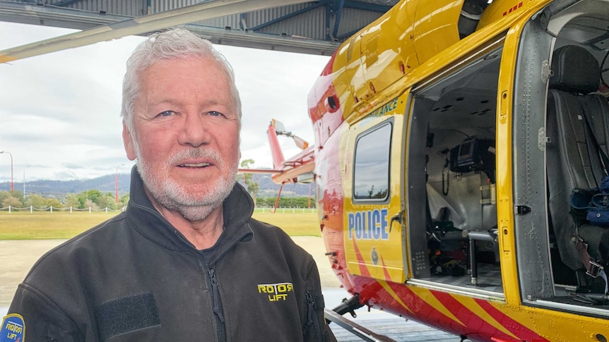Rotor Lift Aviation Chief Pilot Peter McKenzie stands next to a rescue helicopter.