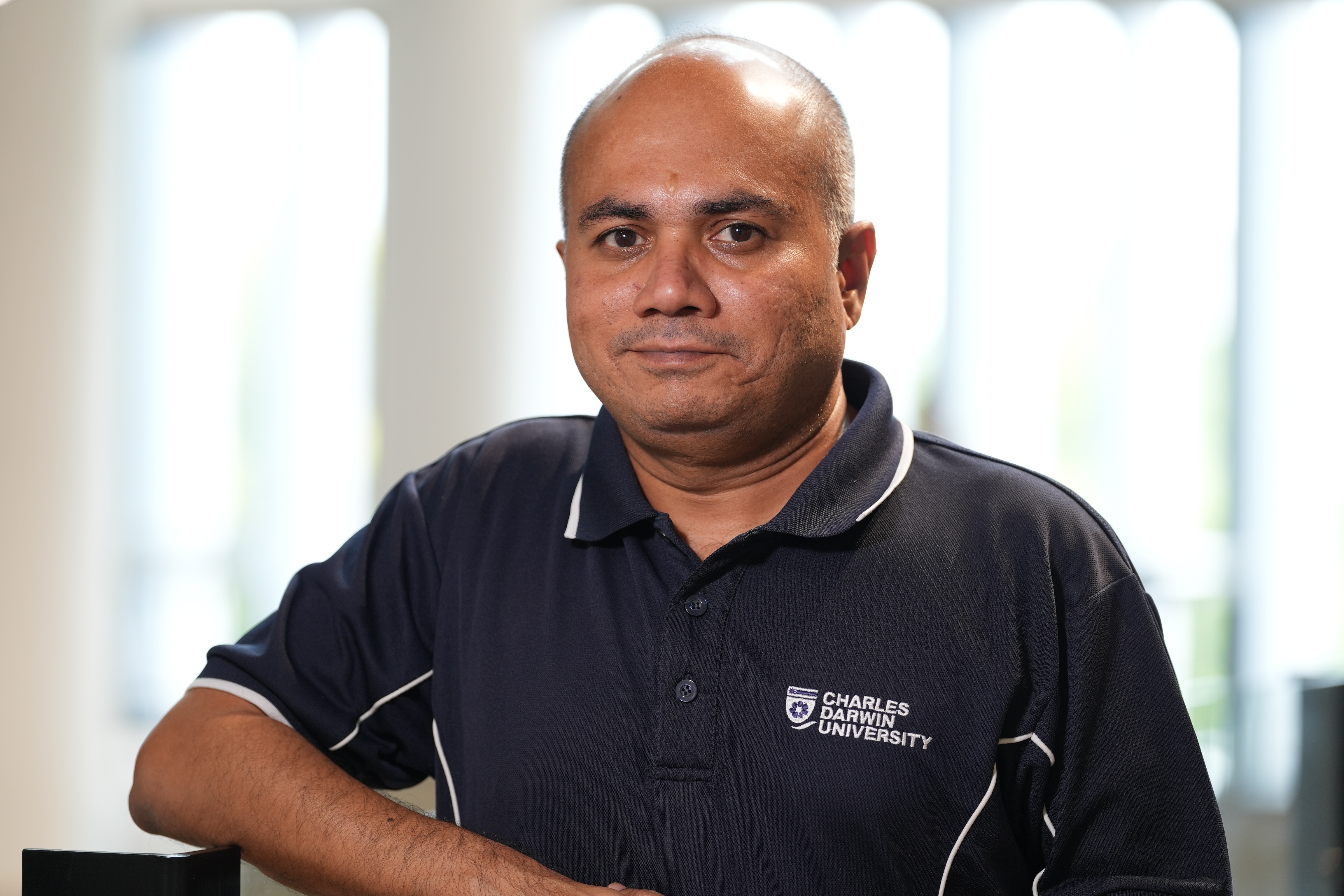 Un hombre con una camiseta polo mira a la cámara.