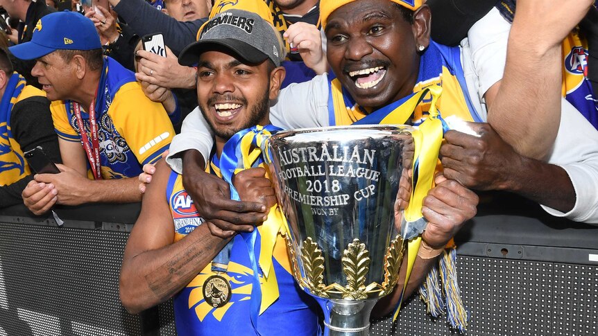 Willie Rioli of the West Coast Eagles holds the premiership trophy with a fan in the crowd after the 2018 grand final.