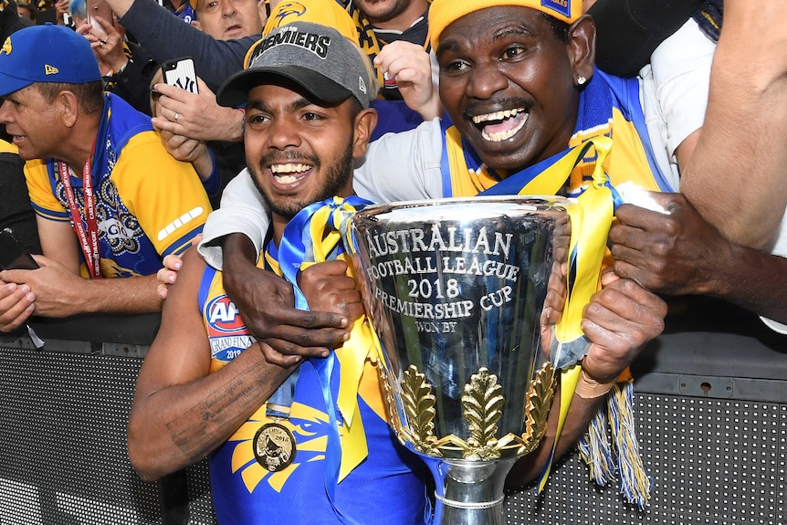 Willie Rioli of the West Coast Eagles holds the premiership trophy with a fan in the crowd after the 2018 grand final.