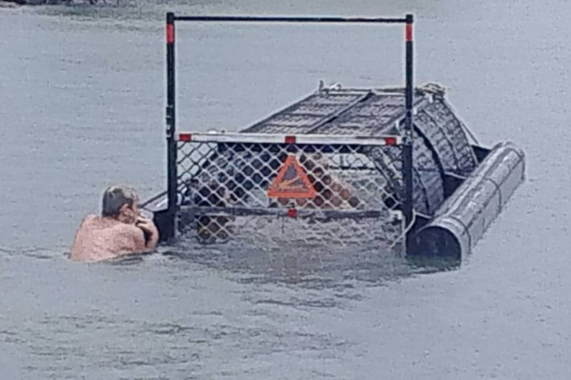 One man watches another man who has swum into and closed a crocodile trap in Port Douglas