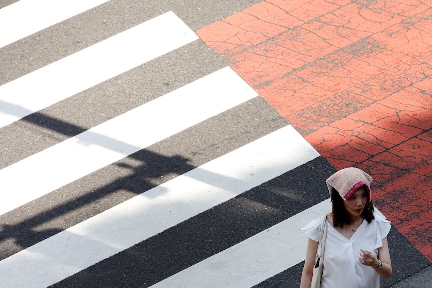 A woman wears a handkerchief on her head on a zebra crossing.