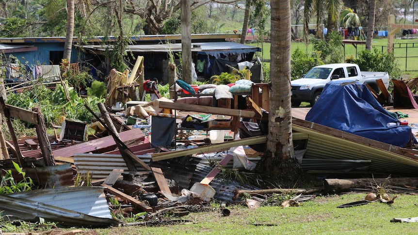Debris from a house lies under trees.
