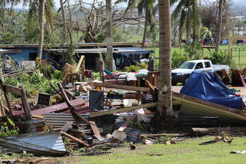 Debris from a house lies under trees.