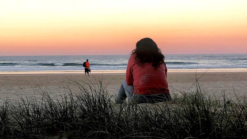 "Jayne" stares at the sunset on a Gold Coast beach. It was on a beach that she was violently assaulted.