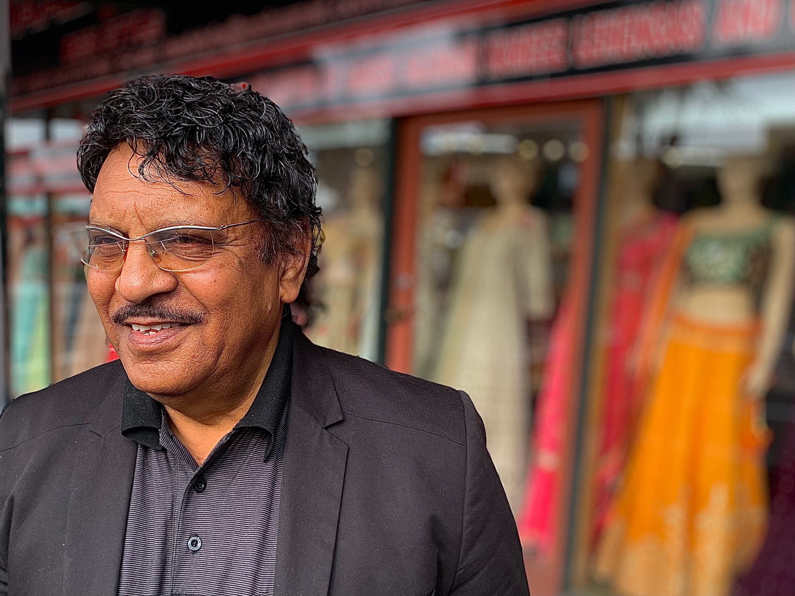 Man in suit stands in front of dress shop
