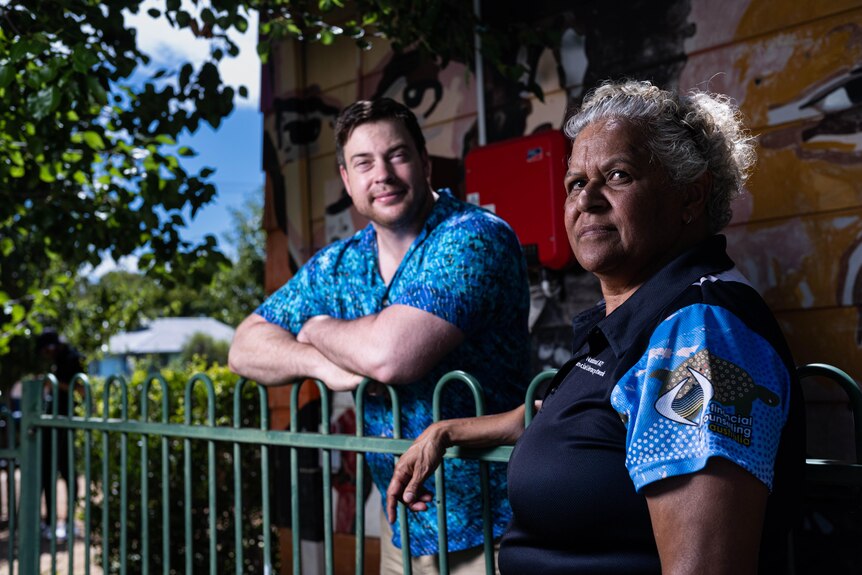 An Aboriginal man and woman stand next to a fence