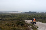 Two riders on a quad bike make their way on a track on Tasmania's west coast.