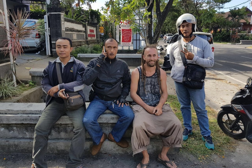 David James Taylor, who is accused of the murder of a Bali policeman, with men assumed to be police.