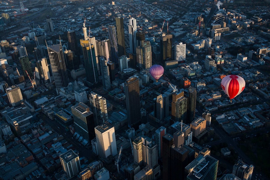 Balloons float amongst skyscrapers in dawn light.