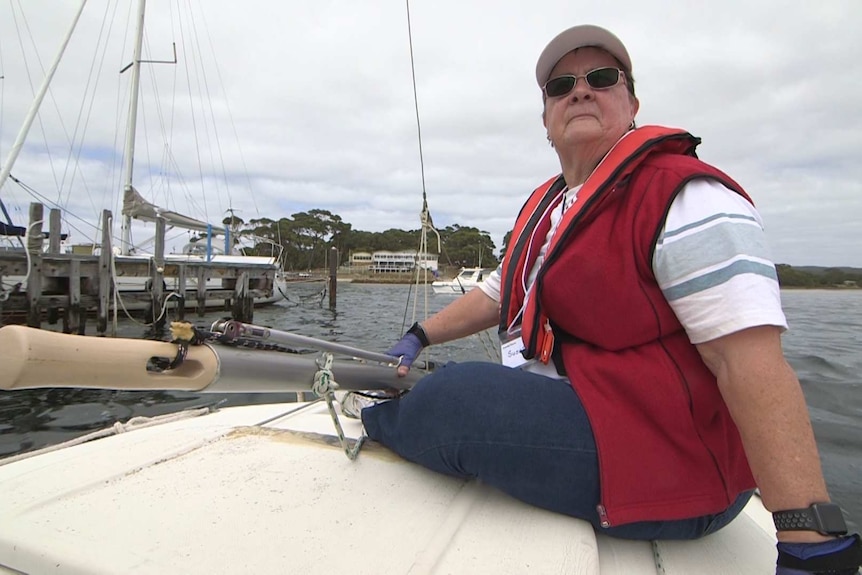 A woman sitting on a sailing boat on the ocean.