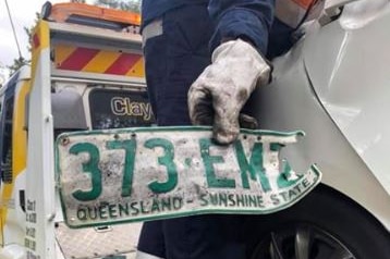 A man holds a licence plate which reads 373 EMZ