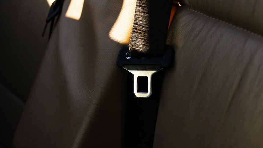 An empty car seat with a seatbelt buckle shining under sunlight