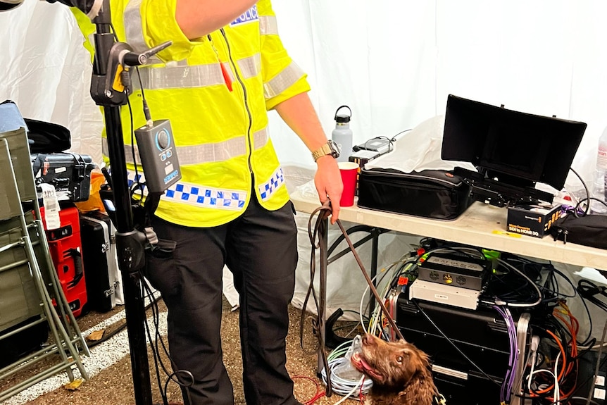 Police officer and sniffer dog in media tent.