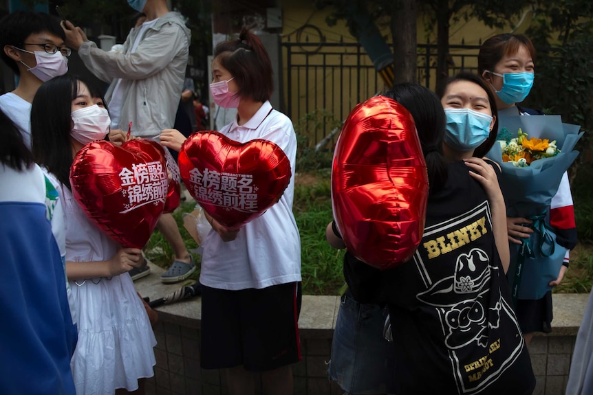 Students hug each other while waiting for exam result outside school