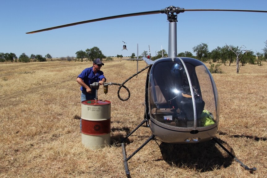 Pilot Matt Gane refuels his helicopter from a 44 gallon drum on Anthony Lagoon Station