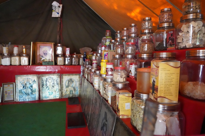 A row of bottles and images of Hindu gods in a tent shop