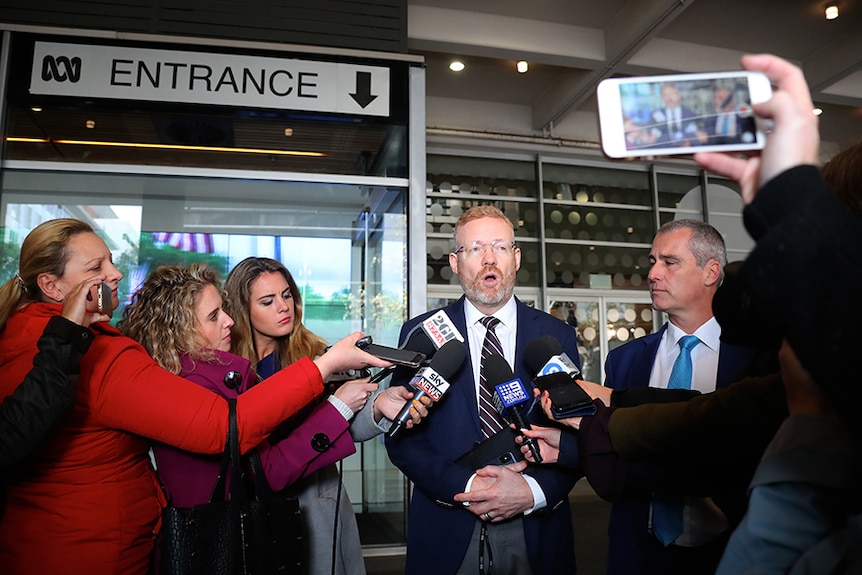 Craig surrounded by journalists and cameras.