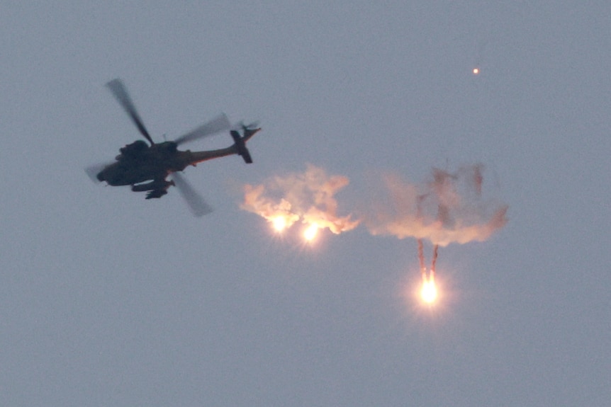 An Apache helicopter fires flares.