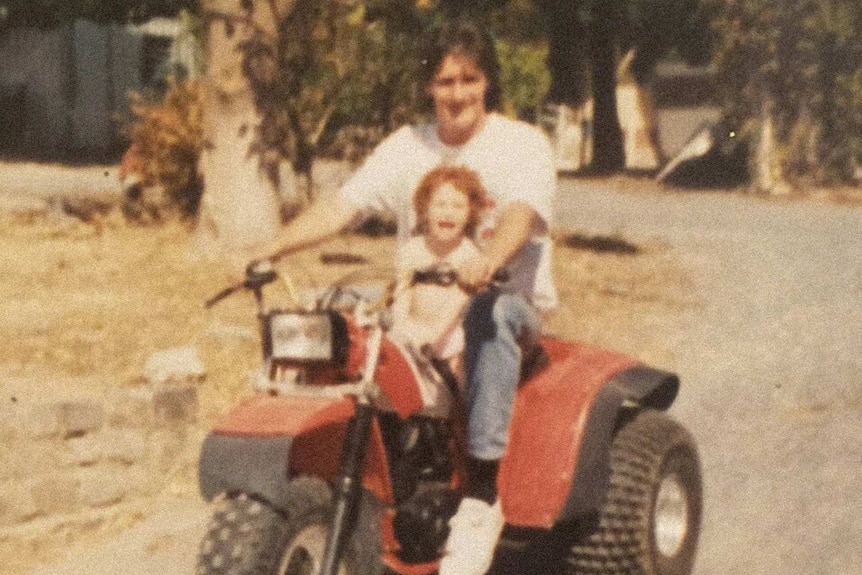 Old grainy photo of a man on a three wheeled motorbike and little girl on the seat in front.