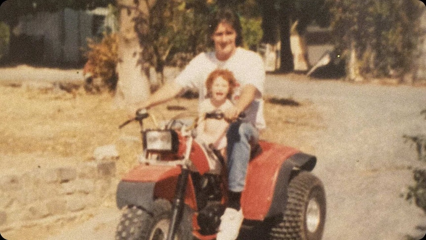Old grainy photo of a man on a three wheeled motorbike and little girl on the seat in front.
